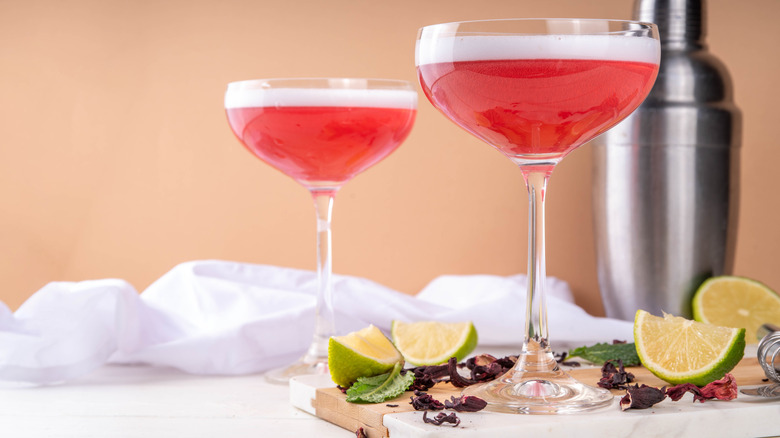 hibiscus margaritas in coupe glasses with petals and spices for garnishes