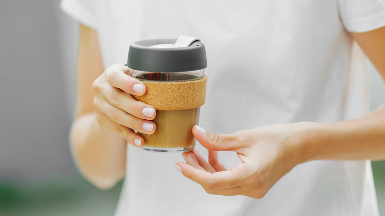 hands hold reusable coffee cup