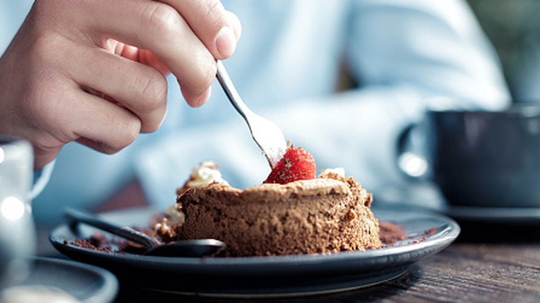 hand of a person eating unspecified cake or dessert with a fork