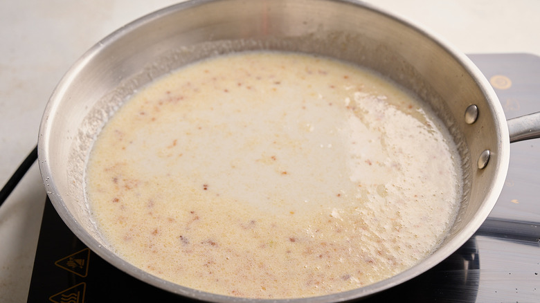 milk in a skillet with garlic and butter
