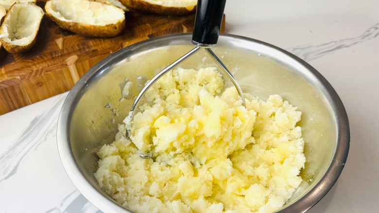 Potatoes and masher in bowl