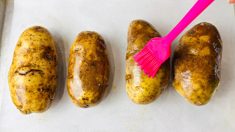Brushing russet potatoes with oil