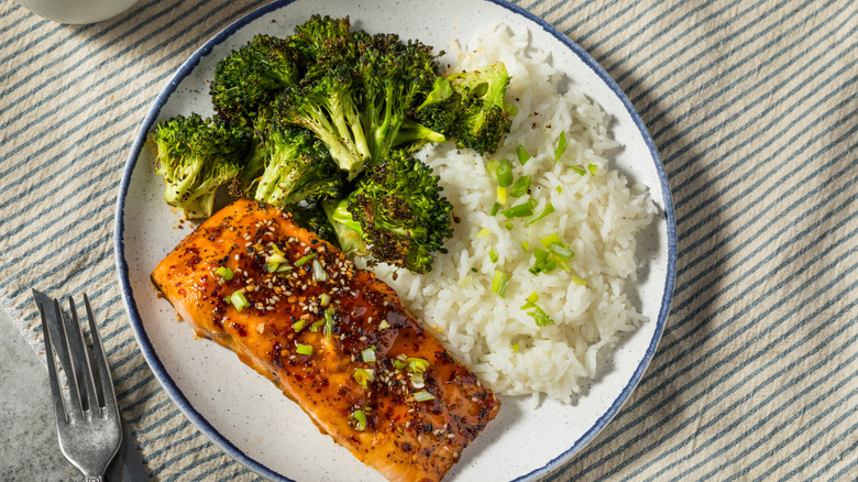 a plate of food with cooked salmon, white rice, and broccoli