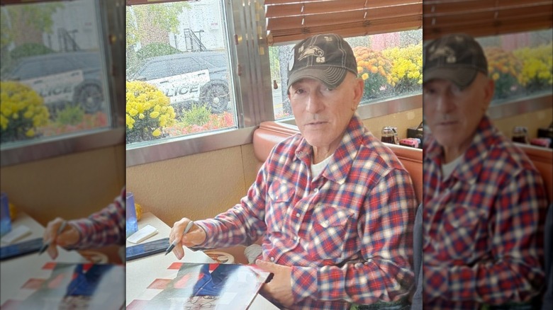 Bruce Springsteen signing an autograph while sat in a diner booth at Roberto's Freehold Grill