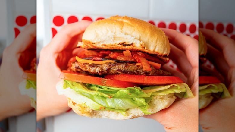 Close-up of hands holding a large cheeseburger from WindMill Hot Dogs
