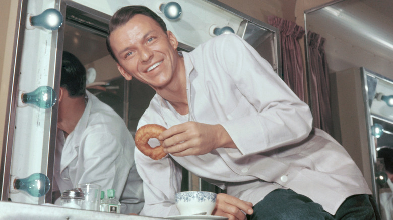 Frank Sinatra in a backstage room eating a donut