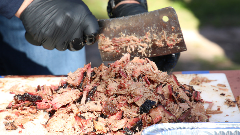 A person chops brisket with a cleaver