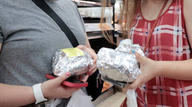 people holding wrapped sandwiches from Buc-Ee's