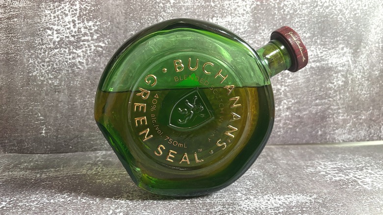 Green bottle of Buchanan's Green Seal tilted on side on black background