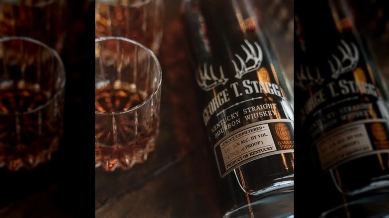 Top-down shot of Buffalo Trace George T. Stagg bottle next to two whiskey glasses on wooden surface