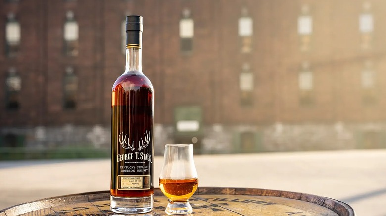 Bottle of Buffalo Trace George T. Stagg next to glencairn glass of whiskey on barrel