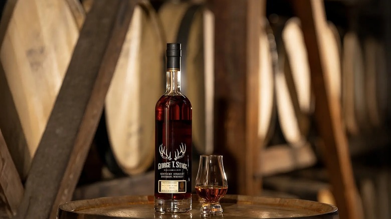 Bottle of Buffalo Trace George T. Stagg next to glencairn glass of whiskey on barrel