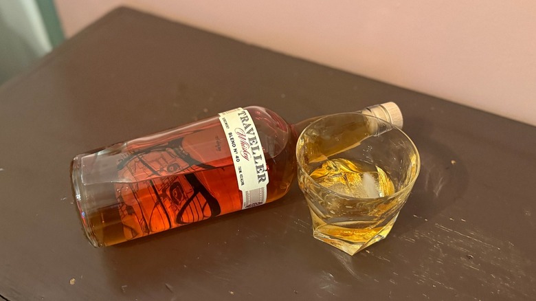 bottle of Buffalo Trace Traveller Whiskey laying on table with glass on the rocks next to it
