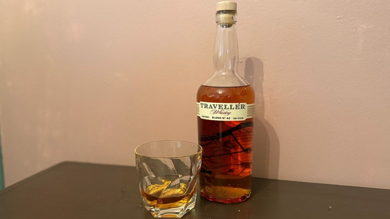 bottle of Traveller Whiskey with a neat glass next to it