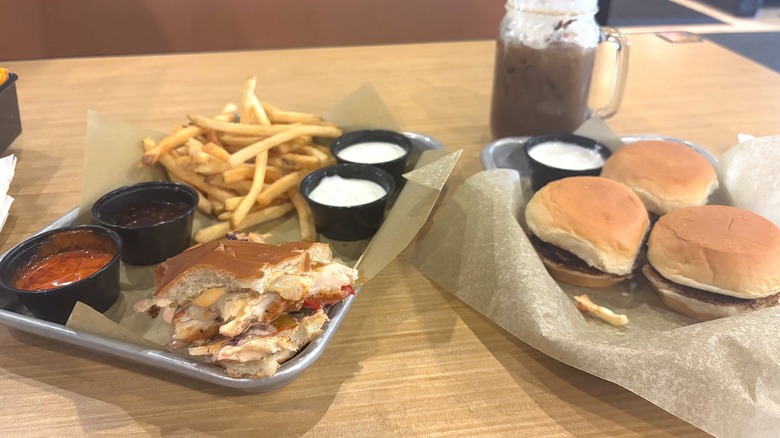 Buffalo Wild Wings sliders, half eaten chicken sandwich, fries, sauces on tray, drink behind