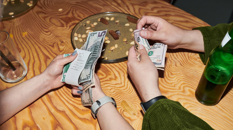 Close up of customers splitting checks at restaurant