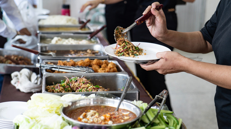 Person loading food on plate at buffet