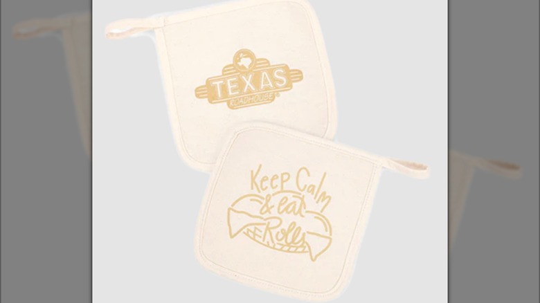 Two beige oven mitts with Texas Roadhouse branding and design