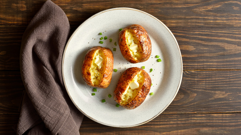 Plate of baked potatoes with butter and chives