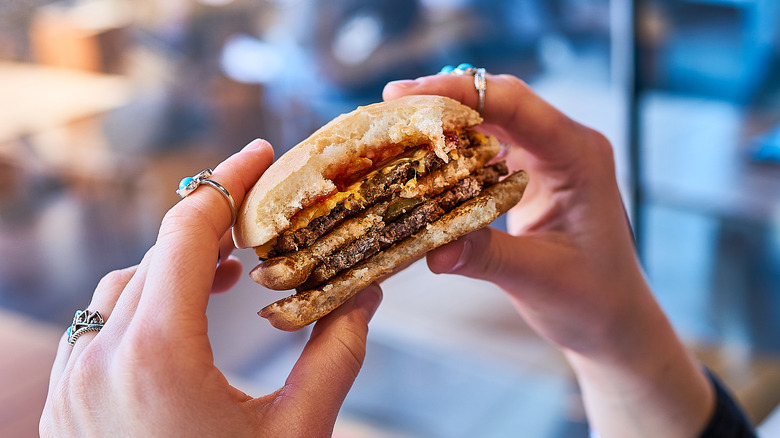 Hands holding fast food hamburger