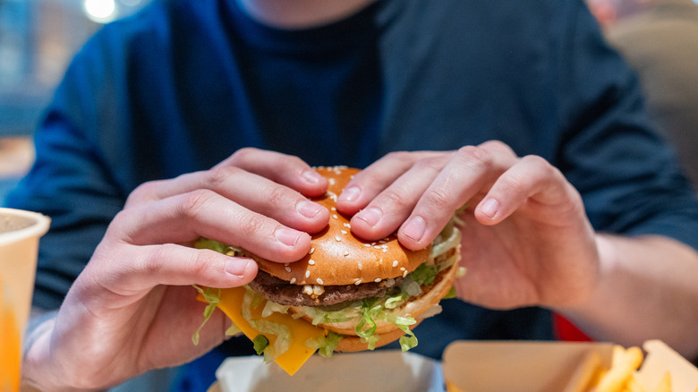 person preparing to bite into fast food burger