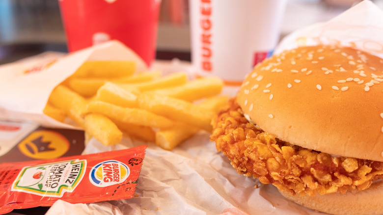 A Burger King bag full of food sits on a table.