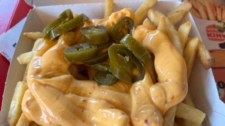 Burger King chili cheese fries are in a basket and topped with jalapenos.