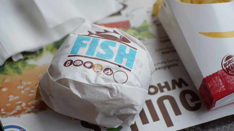 A Burger King Big Fish sandwich sits on a tray next to a carton of french fries