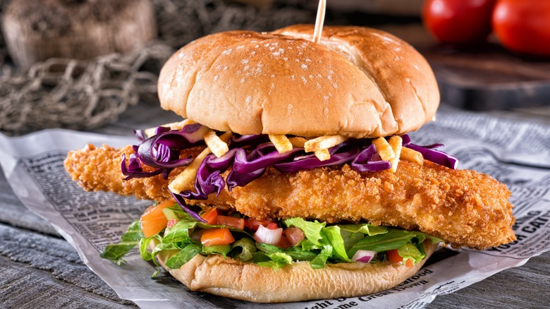 A fish sandwich sits on a piece of newspaper