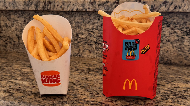 large containers of fries from Burger King and McDonald's standing on counter