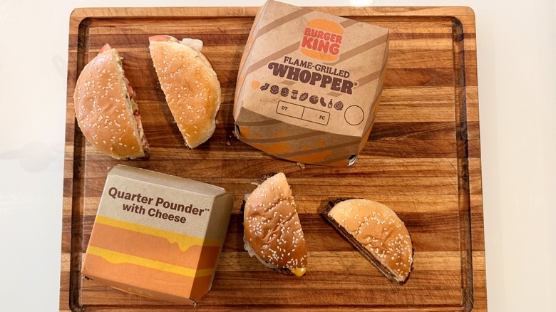 overhead shot of Whopper and Quarter Pounder packaging and sandwiches cut in half on cutting board