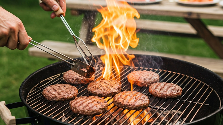A person grilling burger patties outside