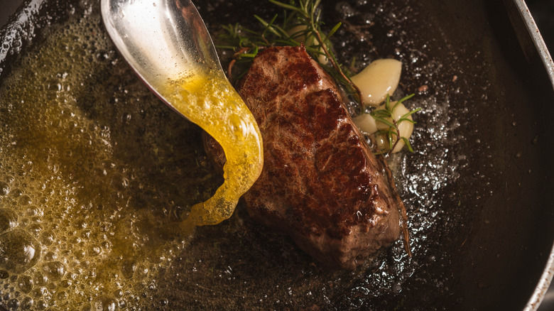 Basting steak with metal spoon.