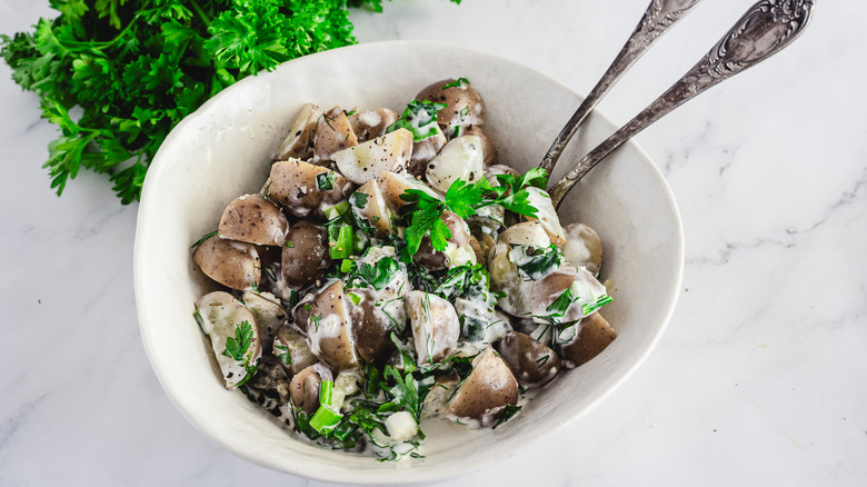 Potato salad in bowl with two spoons and parsley