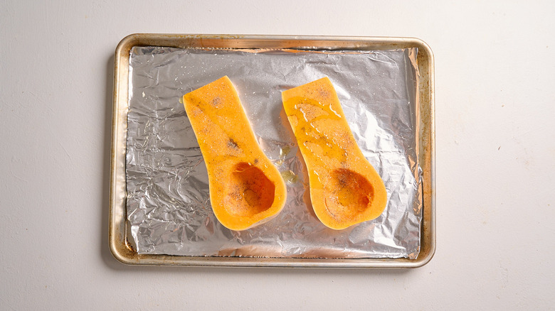 butternut squash halves seasoned on a baking sheet