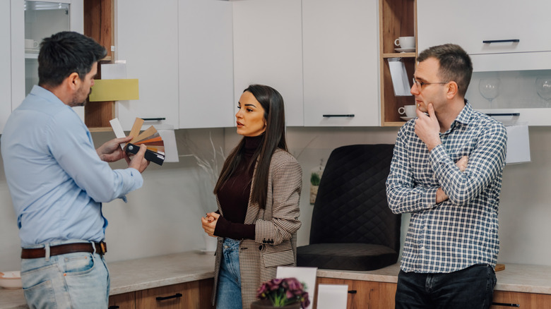 A couple discusses kitchen cabinet colors with contractor