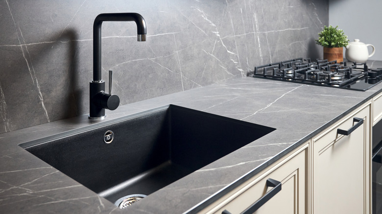 Kitchen counter with a dark soapstone countertop and underset black sink.