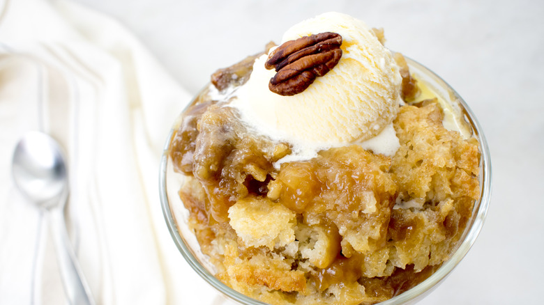 Cobbler in glass dish topped with vanilla ice cream and single pecan