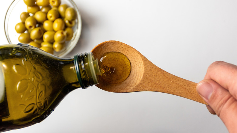 Olive oil pouring wooden spoon