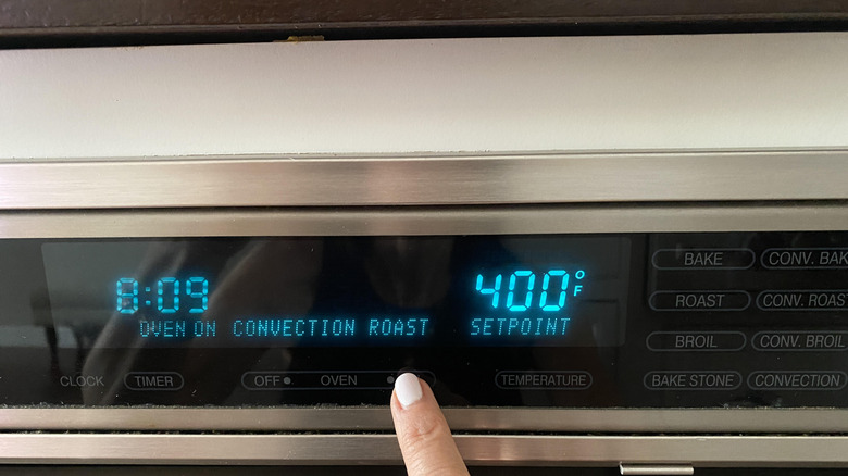 finger setting the oven temperature
