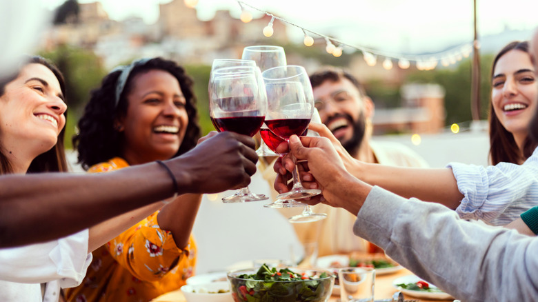 a group of friends dining and toasting with red wine