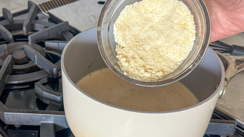 Grated cheese pouring into saucepan
