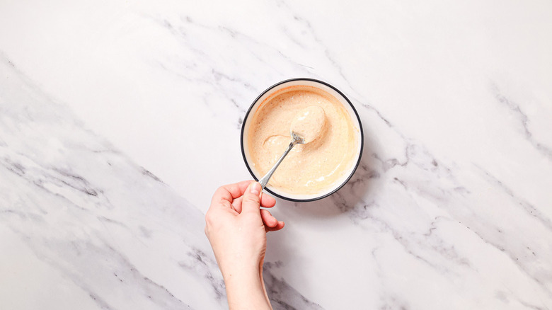 Mixing aioli with spoon