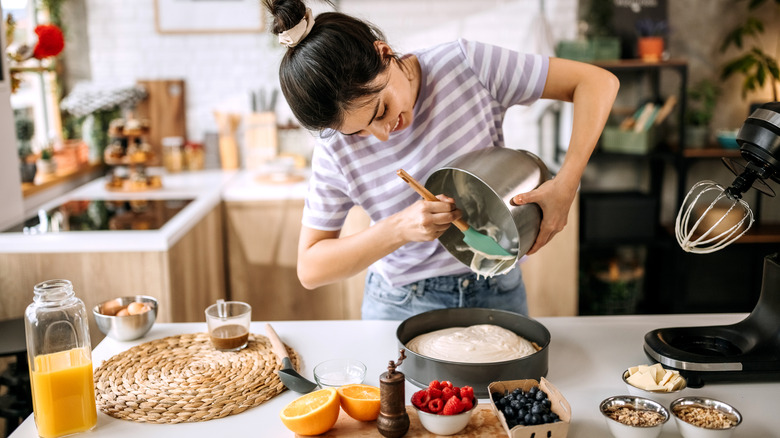 Woman pouring cake batter into pan on counter