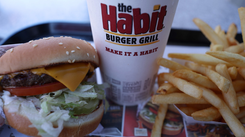 A cup from The Habit Burger Grill sits between a burger and fries