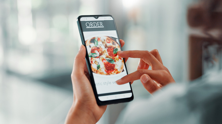 hands holding a phone with a pizza image and "ORDER" text