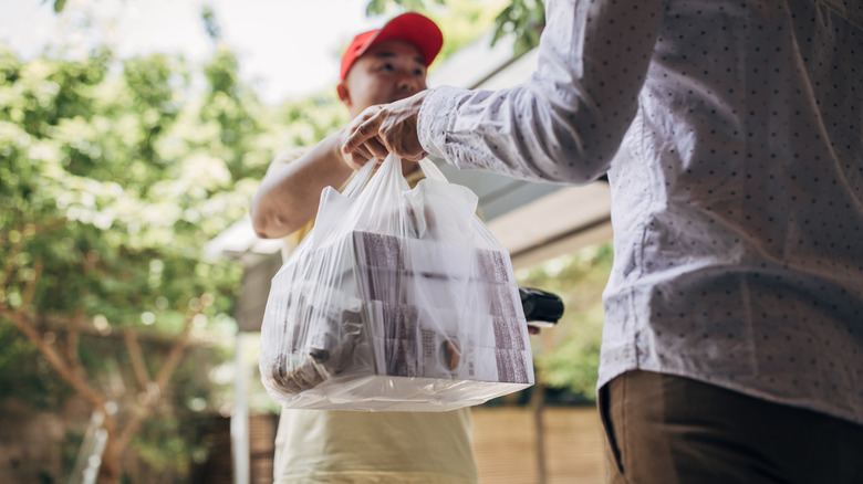 people exchanging a food delivery bag