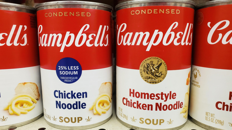 Cans of Campbell's chicken noodle soup lined up on a grocery store shelf