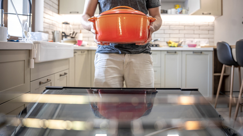 Man preparing to put an orange Dutch oven in his oven