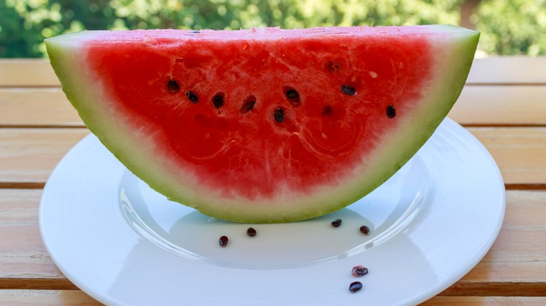 Sliced watermelon with black seeds on a white plate